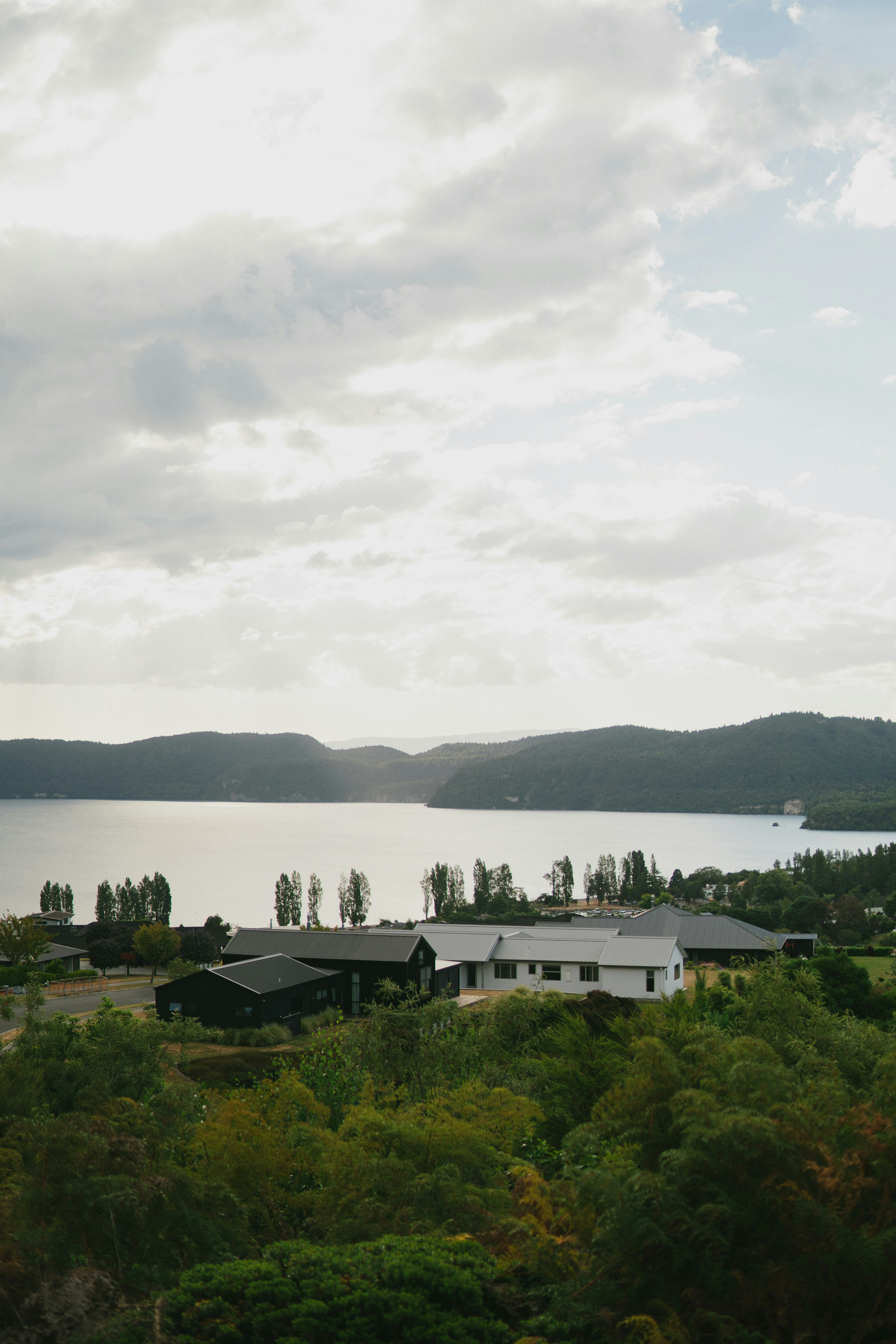 white and black house near body of water under cloudy sky during daytime